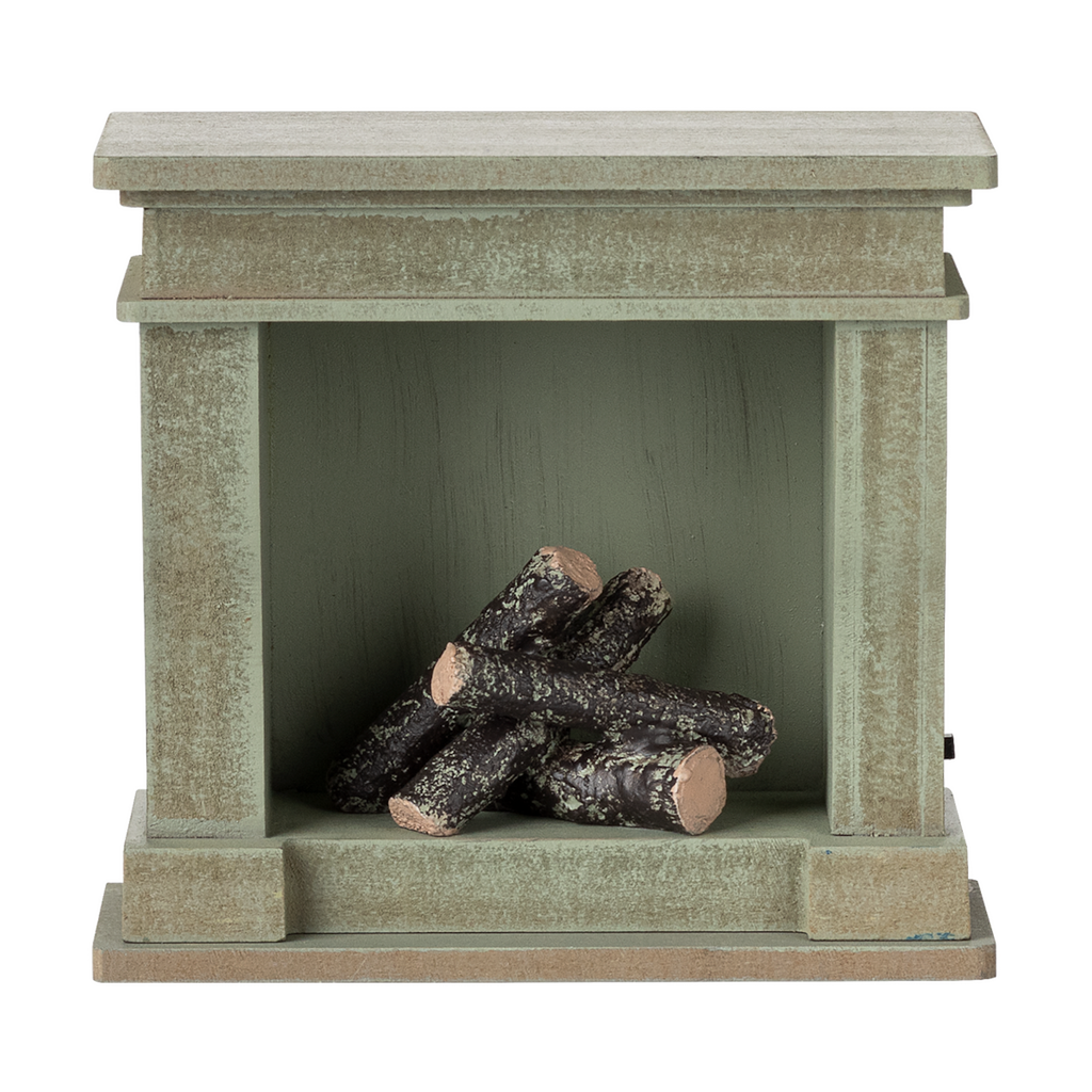 A decorative miniature fireplace with a greenish-gray finish, holding several stacked logs inside, showcasing a cozy and rustic vibe.
