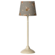 A tall ivory lamp with a gray floral-patterned shade stands against a white background. The lamp has a sleek design, exuding a modern vintage elegance.