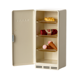Open cream-colored miniature fridge showing toy food: a cookie, sausage, and two ice cream cones. Playful and whimsical tone.
