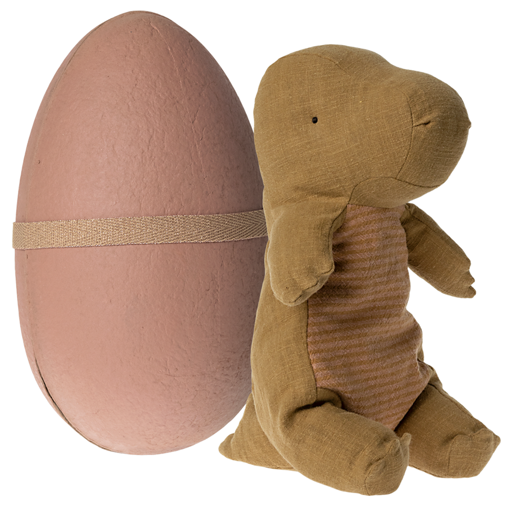 A soft toy dinosaur with a brown body and striped front stands beside a large, pink egg encircled by a beige band, set against a white background.
