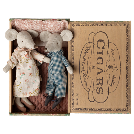 Two fabric mice dolls, one in a floral dress and the other in checkered overalls, lie in a vintage cigar box lined with patterned cloth. Cozy and charming.