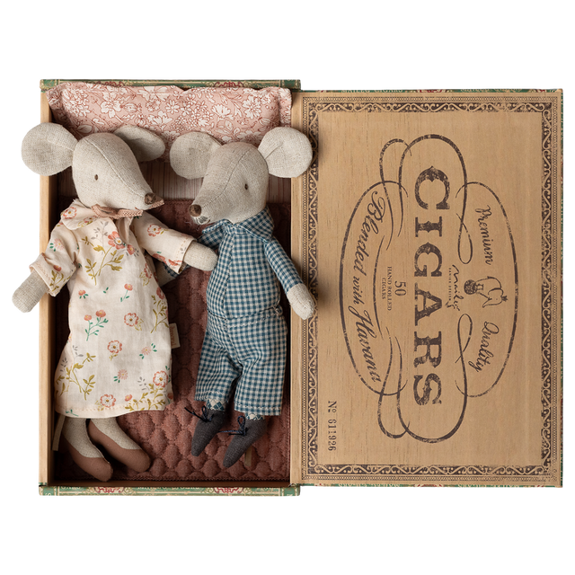 Two fabric mice dolls, one in a floral dress and the other in checkered overalls, lie in a vintage cigar box lined with patterned cloth. Cozy and charming.