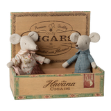 Two fabric mice in vintage clothes sit inside an open wooden cigar box labeled "Havana Cigars." The scene is playful and nostalgic.