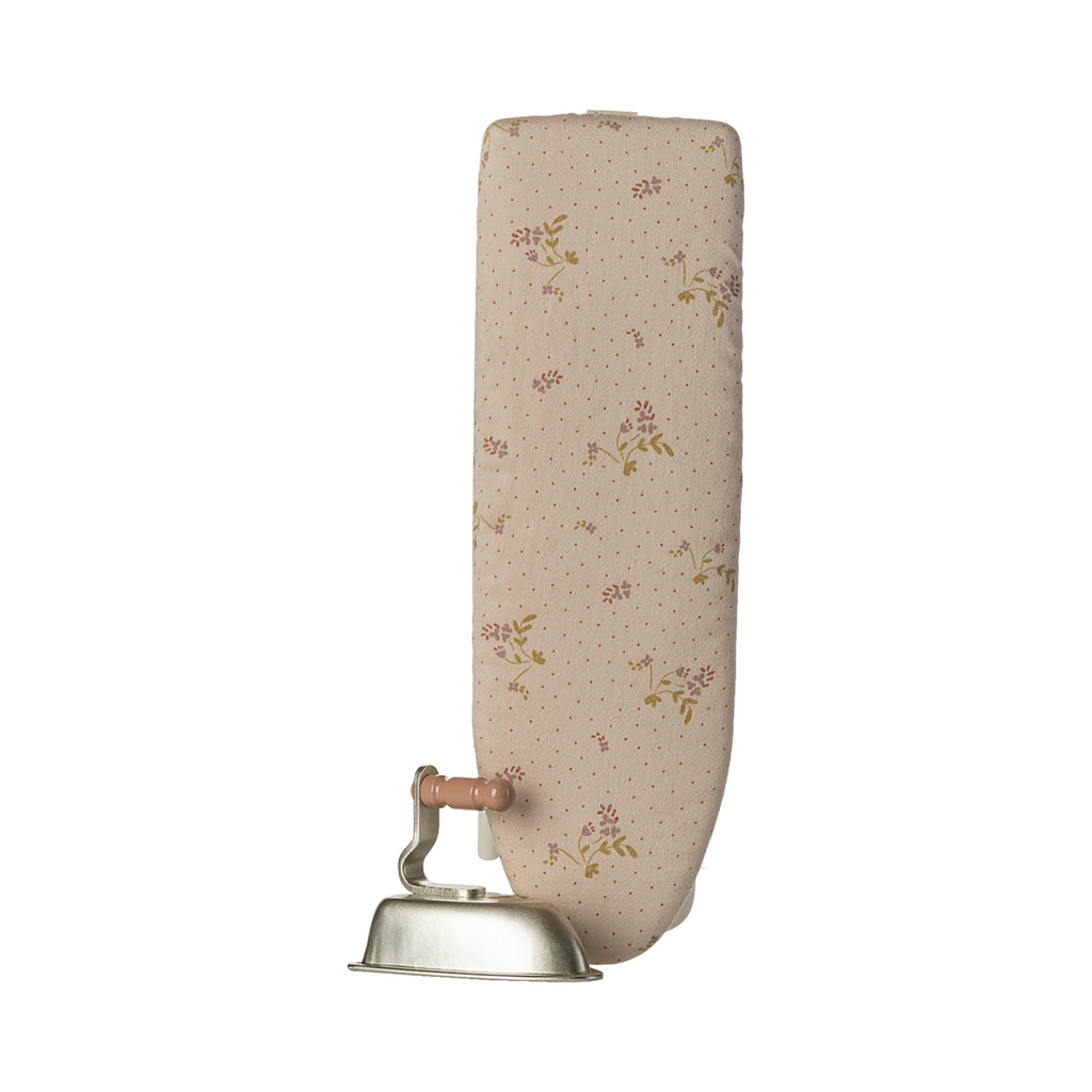 A miniature, foldable ironing board with a floral-patterned surface and a vintage-style iron featuring a wooden handle, set against a plain background.