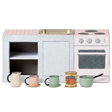 Miniature toy kitchen set with a pink countertop, mini sink, stovetop, and oven. In front are colorful cups, a can of tomatoes, and a small saucepan. Charming and playful.