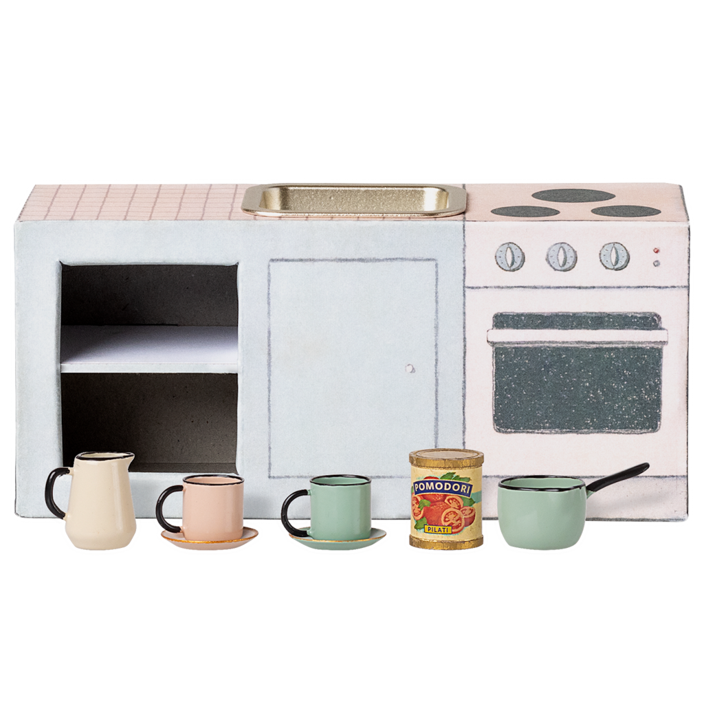 Miniature toy kitchen set with a pink countertop, mini sink, stovetop, and oven. In front are colorful cups, a can of tomatoes, and a small saucepan. Charming and playful.