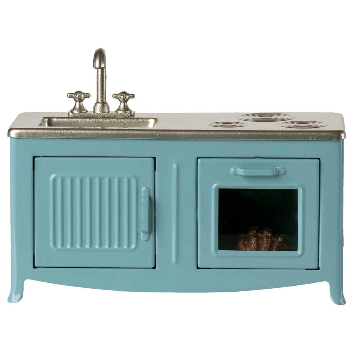 A miniature blue kitchen set with a sink, faucet, and stovetop. An oven with a glass door shows a pie inside. The tone is playful and nostalgic.