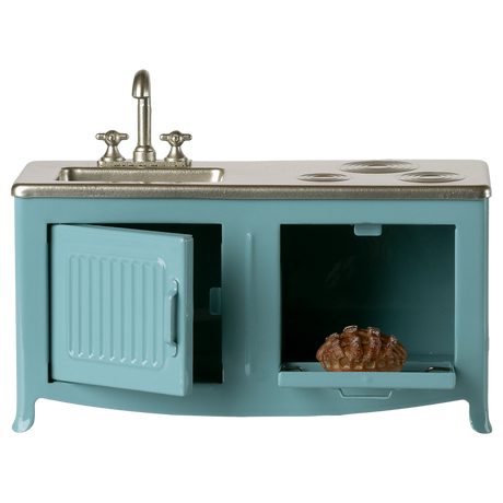 A miniature blue kitchen set with a silver sink and stove. The oven door is open, revealing a small baked pie inside. The simplicity evokes a playful mood.