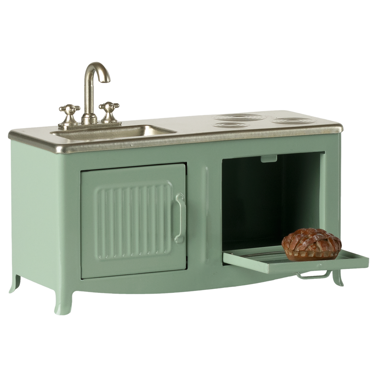 A mint-green toy kitchen set with a small sink, burner marks, and an open oven door revealing a miniature pie. The scene evokes playful nostalgia.