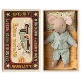 Toy mouse in blue pajamas lies in a matchbox, resembling a cozy bed. The box has vintage-style "Mouse Race" label. Cute and nostalgic.