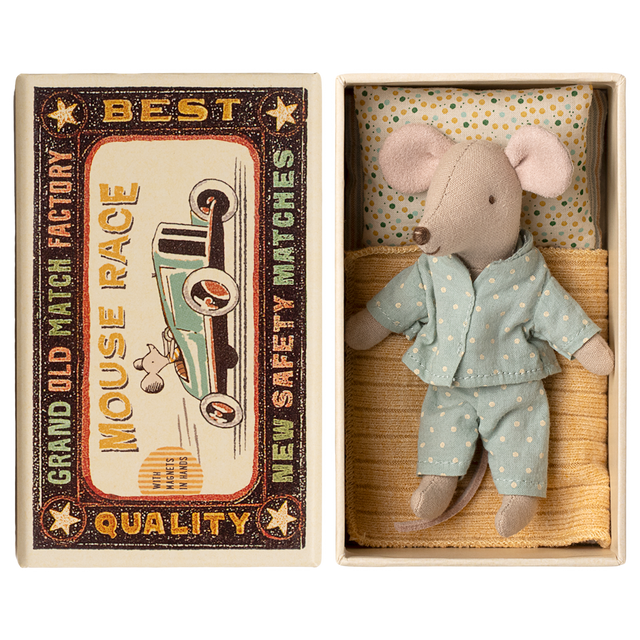 Toy mouse in blue pajamas lies in a matchbox, resembling a cozy bed. The box has vintage-style "Mouse Race" label. Cute and nostalgic.