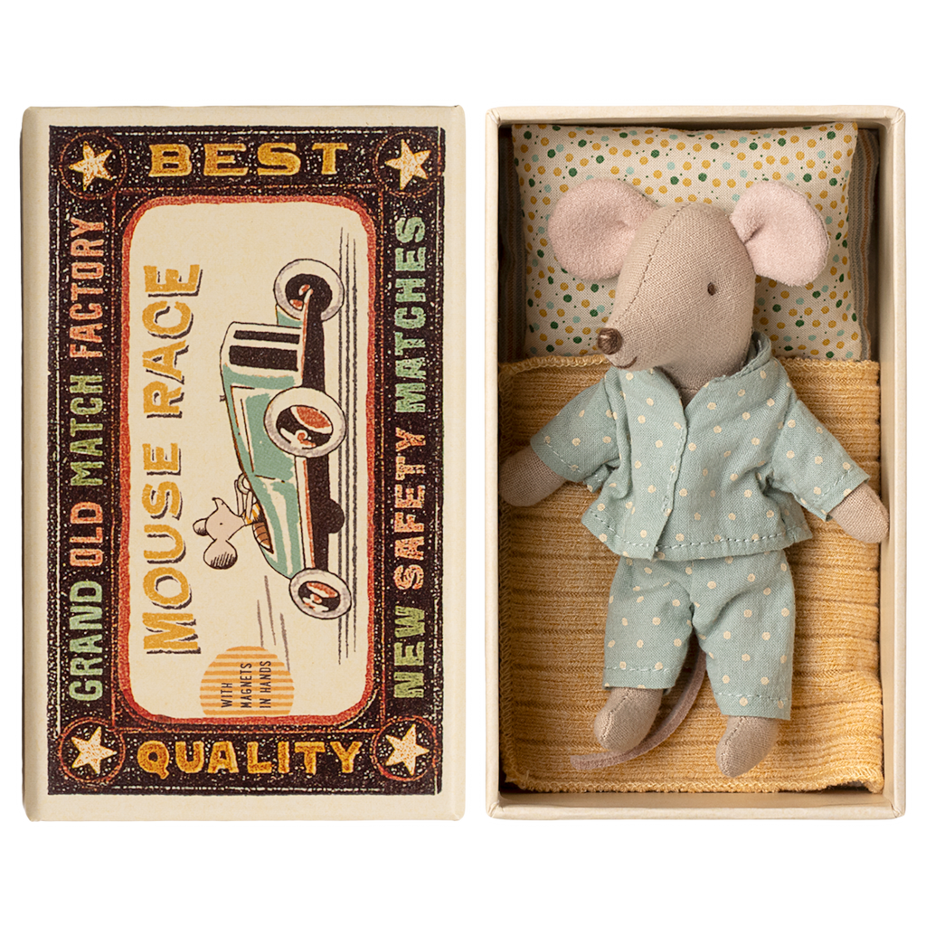 Toy mouse in blue pajamas lies in a matchbox, resembling a cozy bed. The box has vintage-style "Mouse Race" label. Cute and nostalgic.