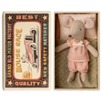 Toy mouse in pink clothes lies in an open matchbox, with vintage race car graphics on the lid. The scene has a nostalgic and whimsical feel.