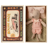 Toy mouse in pink clothes lies in an open matchbox, with vintage race car graphics on the lid. The scene has a nostalgic and whimsical feel.