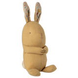 A soft, yellow fabric rabbit toy with long ears featuring a floral pattern sits against a white background. It looks cute and cuddly with stitched features.