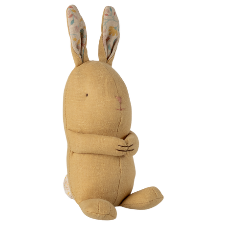 A soft, yellow fabric rabbit toy with long ears featuring a floral pattern sits against a white background. It looks cute and cuddly with stitched features.