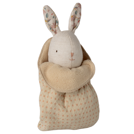 A plush toy rabbit with floral-patterned ears and an embroidered face is snugly swaddled in a soft, polka-dotted beige blanket, set against a white background.