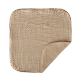 A beige square blanket with rounded corners lies against a white background. It has a subtle checkered pattern and a plush, soft fold in one corner.