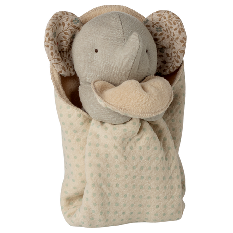 A plush elephant toy with a soft beige body and patterned ears is cozy in a polka-dotted blanket, conveying warmth and comfort against a white background.