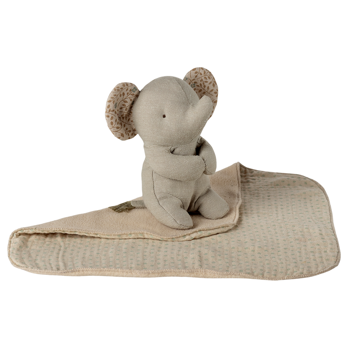 A soft, beige elephant plush toy with patterned ears is sitting on a matching blanket against a white background, conveying a cozy and serene vibe.