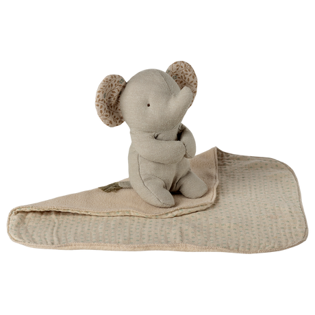 A soft, beige elephant plush toy with patterned ears is sitting on a matching blanket against a white background, conveying a cozy and serene vibe.