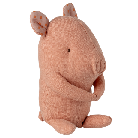 A soft, peach-colored fabric pig toy with small eyes and floppy ears featuring orange polka dots, sitting against a white background.