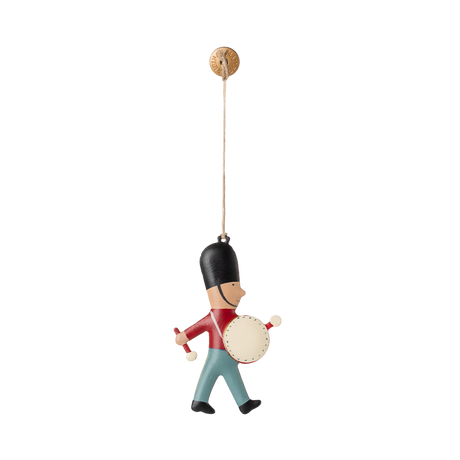 A hanging ornament of a toy soldier wearing a tall black hat, red jacket, and blue pants, playing a drum. The toy is suspended by a string, conveying a playful and cheerful tone.