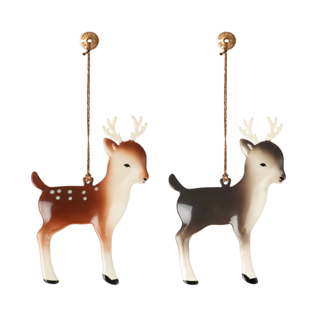 Two Christmas tree ornaments shaped like reindeer, one brown with white spots and the other gray, each hanging from a thin gold string attached to a round gold loop.