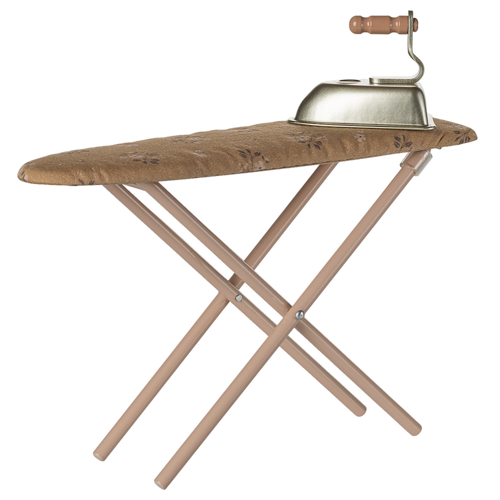 A vintage-style toy ironing board with a patterned, brown cover, and a small metal toy iron with a wooden handle sits on top. The background is white.