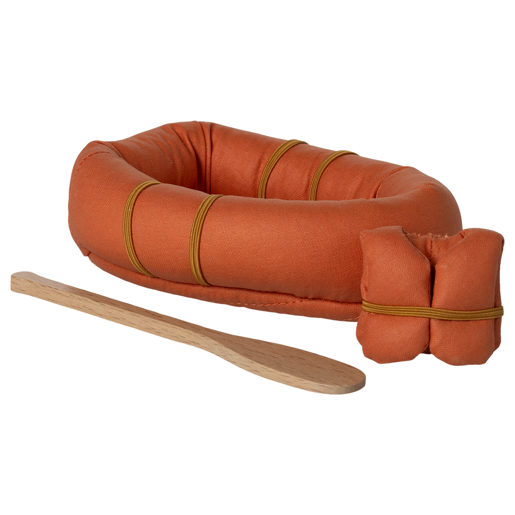 A small, orange, oval-shaped fabric raft with three brown bands is placed on a white background. Beside it lies a simple wooden paddle and lifevest.