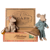Two toy mice in pajamas rest in a cigar box, one in a polka-dot gown and mask, the other in blue stripes. The mood is cozy and nostalgic.