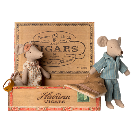 Two toy mice in pajamas rest in a cigar box, one in a polka-dot gown and mask, the other in blue stripes. The mood is cozy and nostalgic.