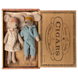 Two toy mice in pajamas rest in a cigar box, one in a polka-dot gown and mask, the other in blue stripes. The mood is cozy and nostalgic.