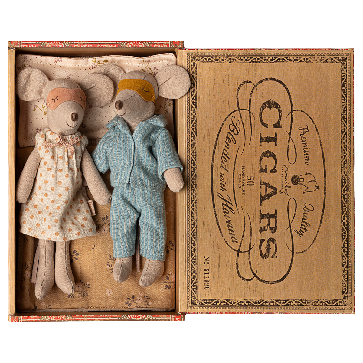 Two toy mice in pajamas rest in a cigar box, one in a polka-dot gown and mask, the other in blue stripes. The mood is cozy and nostalgic.