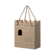 Cardboard gift bag shaped like a castle with a crenelated top. It features a cutout window and the words "Let the Story Begin" printed on it.