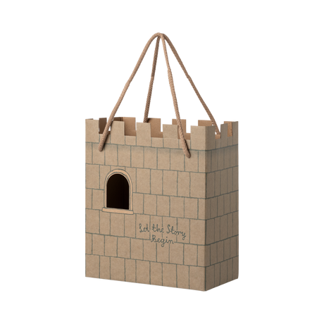Cardboard gift bag shaped like a castle with a crenelated top. It features a cutout window and the words "Let the Story Begin" printed on it.