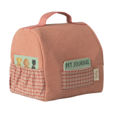 A soft pink fabric bag with a red checkered pocket on each side. One pocket holds a pet-themed card; the other has a "Pet Journal" notebook.