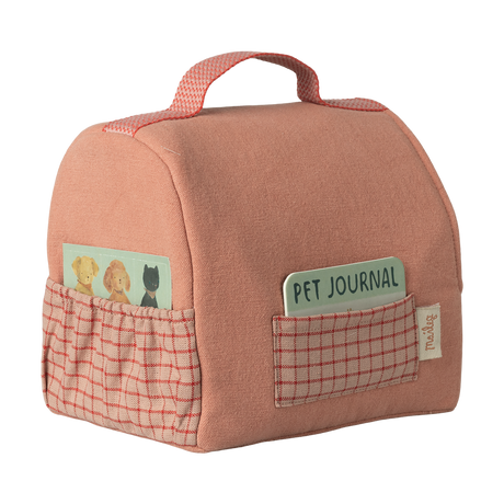 A soft pink fabric bag with a red checkered pocket on each side. One pocket holds a pet-themed card; the other has a "Pet Journal" notebook.
