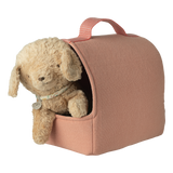 A plush teddy bear peeks from a cozy, pink fabric carrier with a handle, set against a white background, conveying warmth and comfort.
