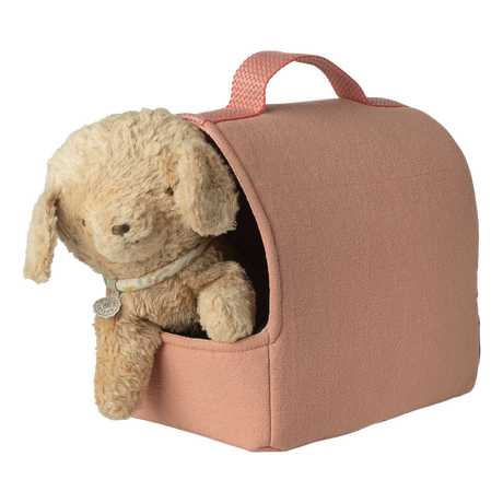 A plush teddy bear peeks from a cozy, pink fabric carrier with a handle, set against a white background, conveying warmth and comfort.