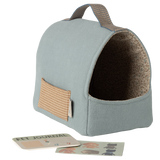 Light blue fabric pet carrier with a brown patterned interior and a small external pocket. A pet journal and stickers lie in front, all set against a white background.