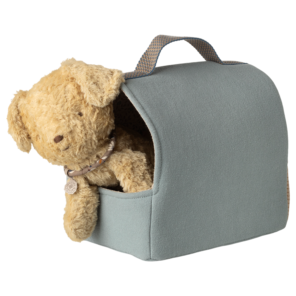 A fluffy brown teddy bear peeks out of a light blue, fabric carrier with a handle. The setting is whimsical and cute against a white background.