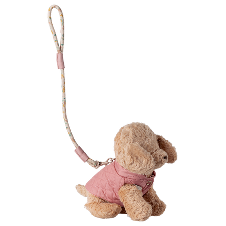 Plush dog keychain wearing a pink quilted jacket, attached to a floral-patterned strap. Set against a white background, conveying a cute, stylish vibe.