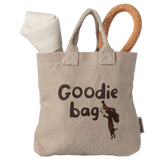 Beige fabric bag with "Goodie bag" text and dog graphic. Rolls of white and brown fabric peek out, creating a playful, cozy feel.