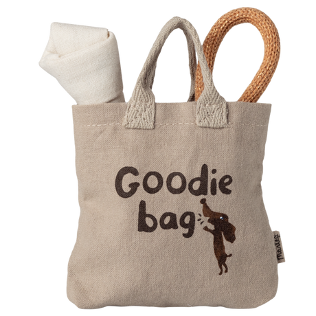 Beige fabric bag with "Goodie bag" text and dog graphic. Rolls of white and brown fabric peek out, creating a playful, cozy feel.