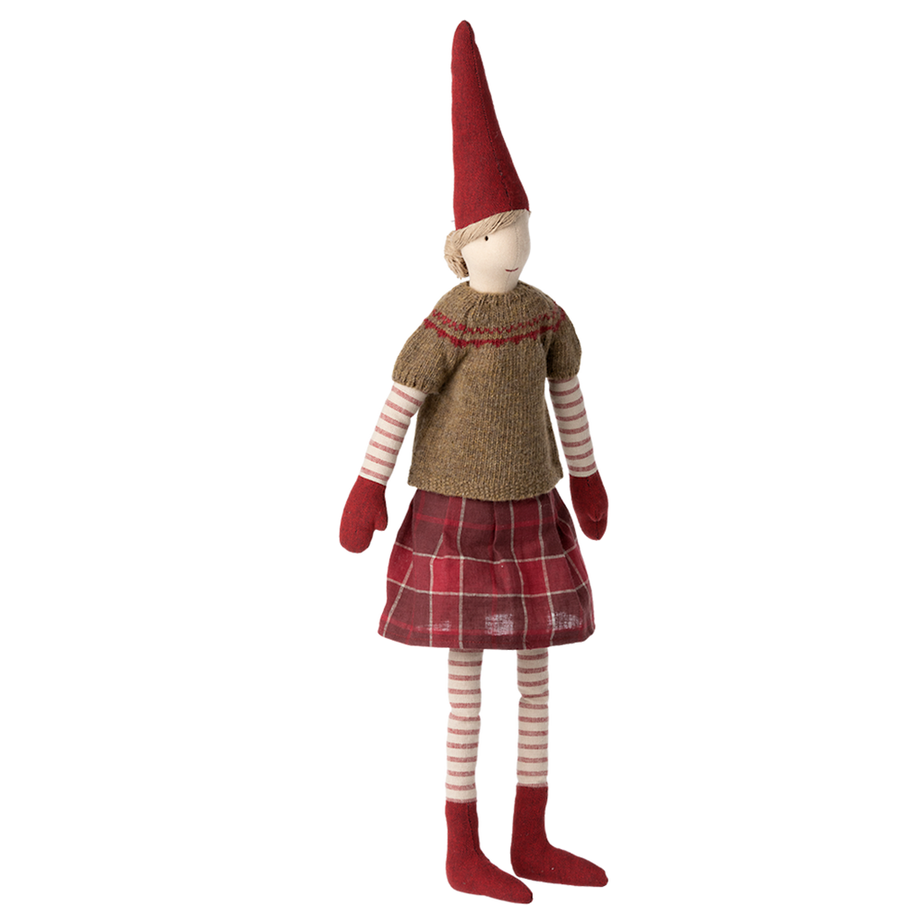 A whimsical cloth doll with a pointed red hat stands against a white background. It wears a knitted sweater, plaid skirt, and striped leggings, conveying a cozy, festive vibe.