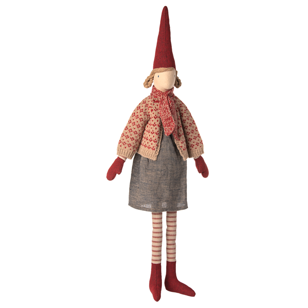 A whimsical cloth doll with a tall red hat, red mittens, and striped stockings. It wears a knitted sweater, scarf, and grey dress against a white background.