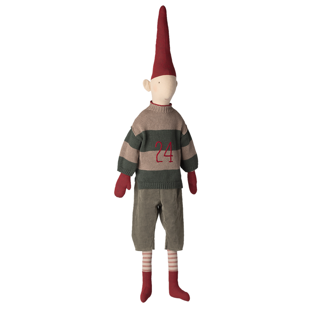 Toy doll in a dark setting, with a tall red hat, striped sweater featuring "24," gray pants, red gloves, striped socks, and red shoes, conveying whimsy.