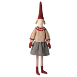 Whimsical doll with a tall red hat, beige sweater with red details, gray skirt, red mittens, and striped leggings, set against a white background.