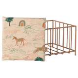 Fabric with a whimsical pattern of horses, trees, and rainbows on a beige background. A pink metal wire grid crate is partially visible on the right.